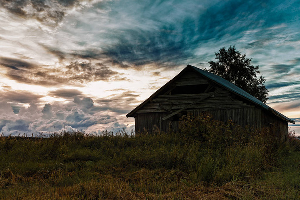 The dramatic clouds gather on the summer sky at the rural Finland. The old barn house is waiting for the harvest time. - Fotó, kép