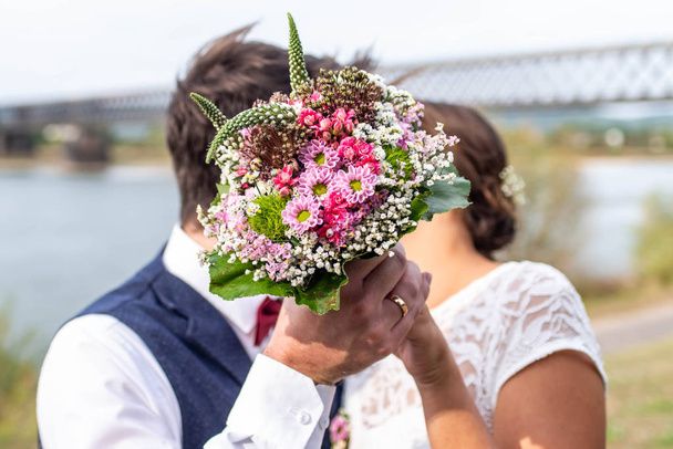 Vue latérale d'un couple amoureux embrassant derrière un bouquet dans le jardin
 - Photo, image