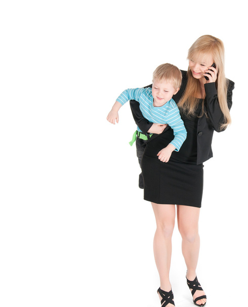 電話で話すと、白い背景の上の腕の下の彼女の息子を運ぶ若いビジネス女性 - 写真・画像