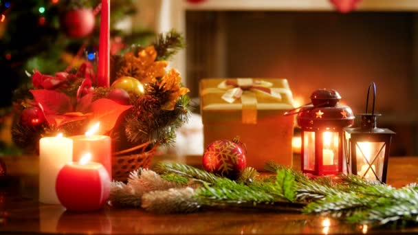 Detailní video z krásné zdobené vánoční stůl se svíčkami a dárky proti zářící vánoční strom a hořící krb - Záběry, video