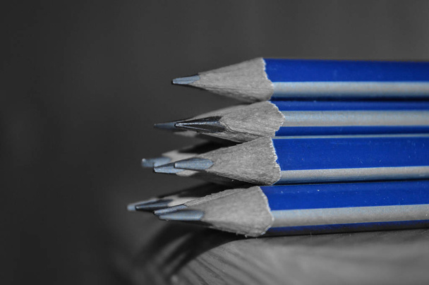 Pencils with sharpened tips kept on a table. Black and white photo with selective blue colour - Photo, Image