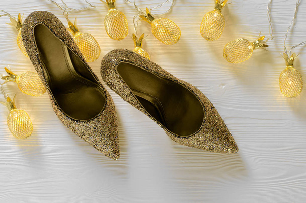 Womens gold chunky glitter pumps. Shoes for wedding, christmas, new year, evening, cocktail, night out. Golden stiletto heels. Flat lay. Footwear on white wooden background with copy space - Foto, Imagem