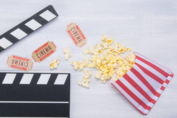 two tickets to the cinema, on a wooden background in the arrangement of the movie clapper with a row strewn with popcorn - Foto, Bild