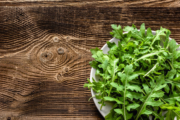 Green vegetables. Organic fresh arugula leaves on plate, vegan food concept - Foto, imagen
