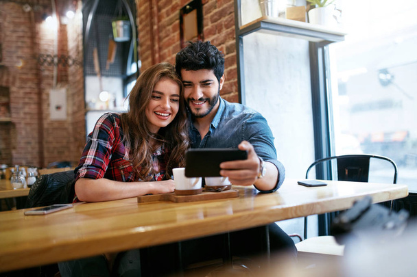 Couple Using On Phone In Cafe For Video Calling Or Taking Photos - Foto, immagini