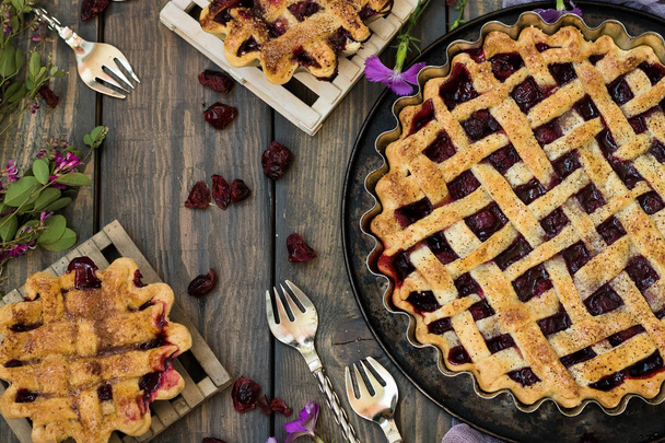 Традиционный американский вишнёвый пирог и мини-пироги на тёмном деревянном фоне
 - Фото, изображение