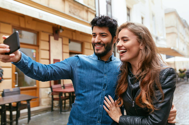 Couple Using Phone On Street, Taking Photos Or Video Calling - Фото, зображення