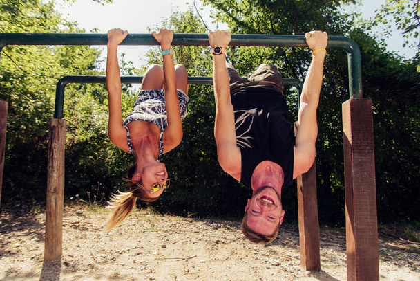 Sterke man en atletische vrouw bezig met fitness en sport uitoefenen in outdoor sportschool - Foto, afbeelding