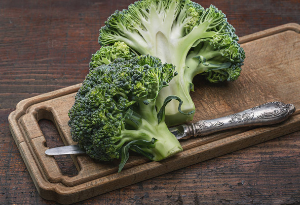 Head of cabbage on cutting board. Knife for cooking vegetables. Broccoli on cutting board. View from above. Cut inflorescence of broccoli. - Photo, Image