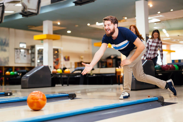 Happy friends having fun and enjoying playing bowling together - 写真・画像