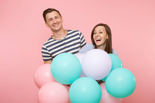 幸せな笑みを浮かべてカップル愛の肖像画。女性と誕生日の祝日を祝う青い服の男は、カラフルな気球とパステル ピンクの背景に党します。人々 の心から感情の概念 - 写真・画像