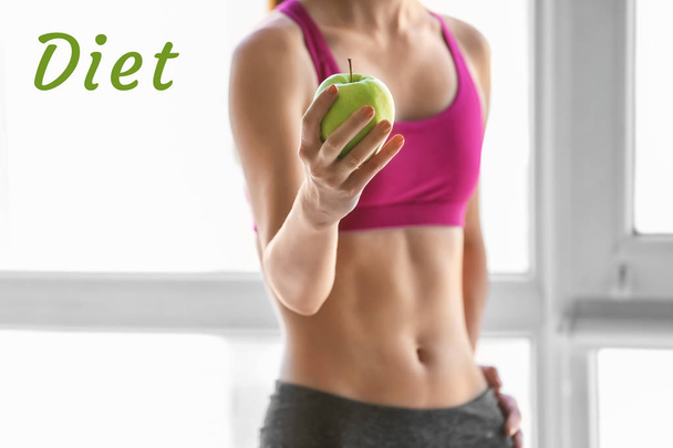 Sporty young woman with fresh apple indoors. Diet concept - Photo, Image