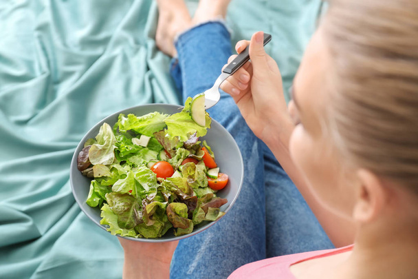Fiatal nő eszik saláta ágyon. Diéta élelmiszer koncepció - Fotó, kép