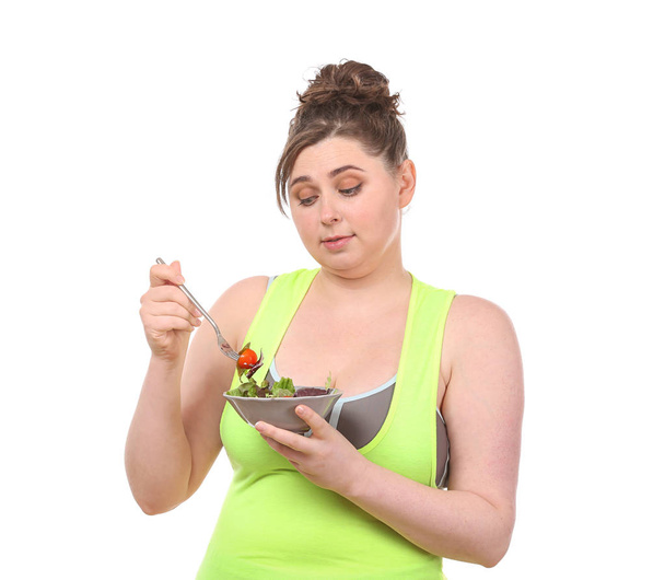 Joven mujer robusta comiendo ensalada sobre fondo blanco. Concepto de alimentación dietética
 - Foto, Imagen