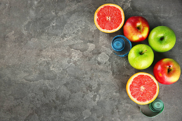 Früchte und Maßbänder auf grauem Hintergrund. Ernährung - Foto, Bild
