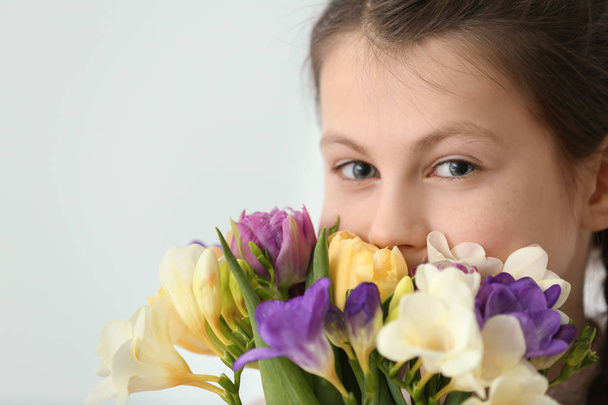 Little girl with bouquet of flowers on light background, closeup - 写真・画像