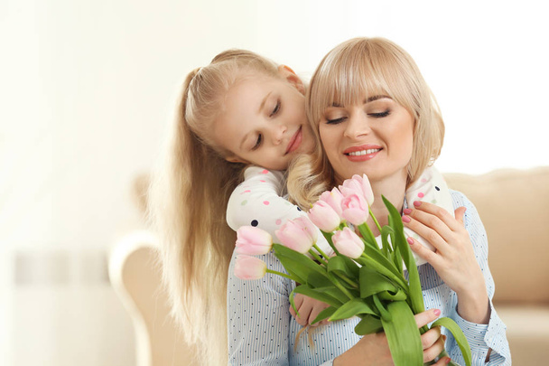 Portrait of cute little girl and her mother with tulip bouquet at home - Fotoğraf, Görsel
