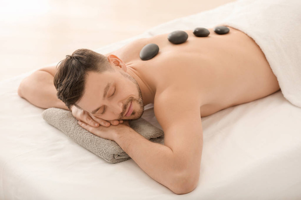 schöner Mann mit Steinmassage im Wellness-Salon - Foto, Bild