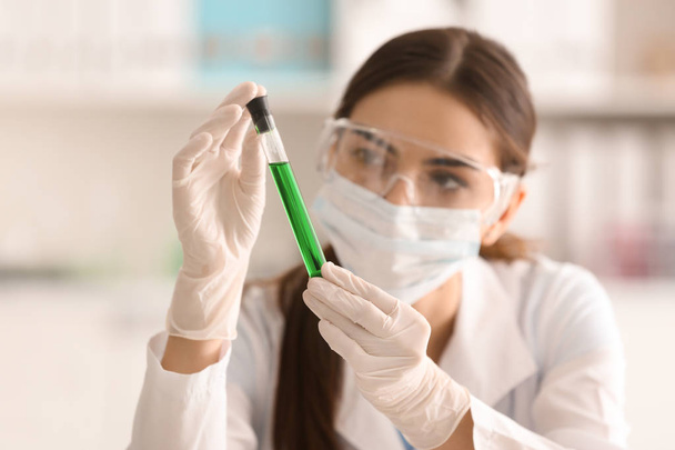 Жінка-вчена тримає пробірку з кольоровим зразком в лабораторії
 - Фото, зображення