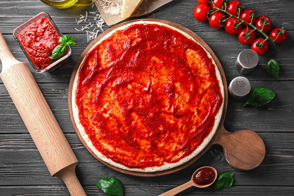 Kompozycja z pomidor smaczny sos na podłoże drewniane i ciasto do pizzy - Zdjęcie, obraz