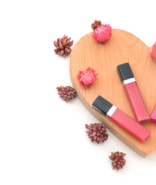 Beautiful lip glosses with wooden heart and flowers on white background - Photo, Image