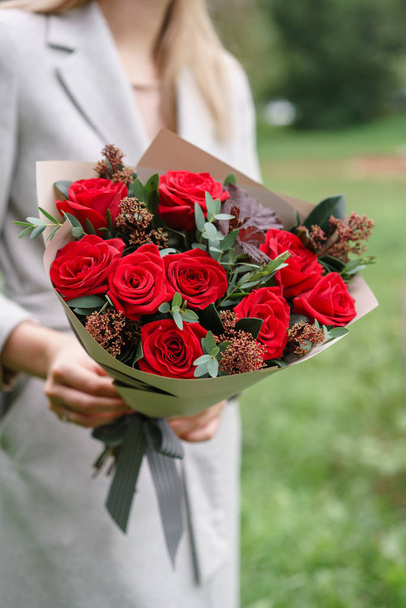 Bella donna che tiene un bellissimo bouquet autunnale. disposizione floreale con garofani e rose rosse da giardino. Colore rosa. prato verde su sfondo
 - Foto, immagini