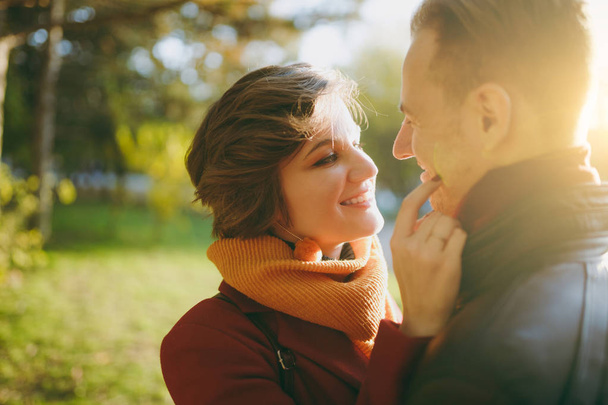 Close up of Young romantic couple smiling woman man in casual clothes embracing looking at each other on walk in autumn city park outdoors in sunny day. Love relationship family lifestyle concept - Photo, Image