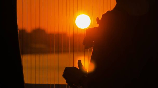 Frau spielt Harfe bei Sonnenuntergang - Foto, Bild