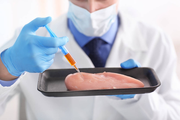 Scientist with syringe examining meat sample in laboratory - Foto, afbeelding