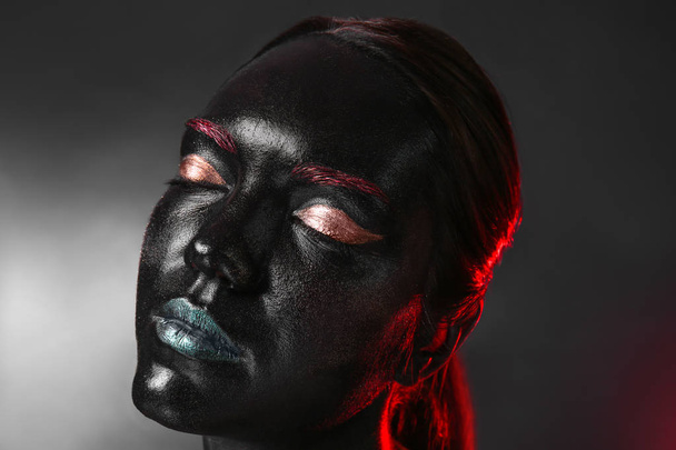 Portrait of beautiful young woman with surreal makeup on dark background - Photo, Image