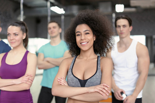 Sporty girl with group of athletes in gym - Photo, Image