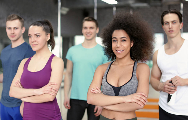 Sporty girl with group of athletes in gym - Photo, Image