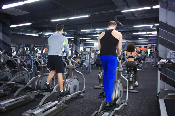 Personas que hacen ejercicio en máquinas de entrenamiento en el gimnasio
 - Foto, imagen
