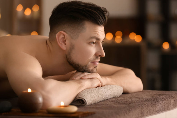 Giovane uomo rilassante sul lettino da massaggio nel salone spa
 - Foto, immagini