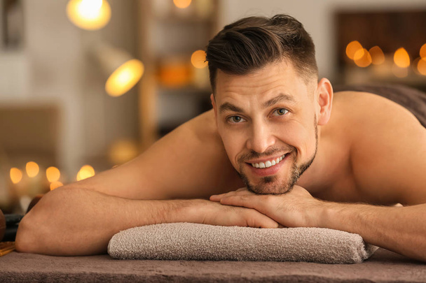Young man relaxing on massage table in spa salon - Photo, image
