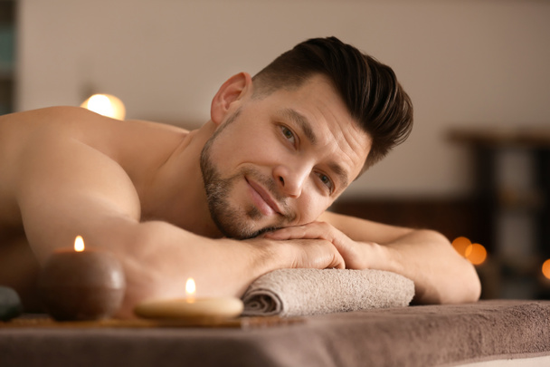 Young man relaxing on massage table in spa salon - Photo, Image
