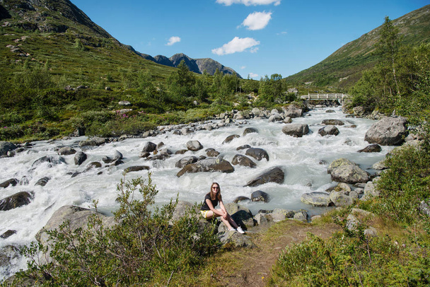 Besseggen ridge Jotunheimen Milli Parkı, Norveç'te dağ nehir kenarında oturan uzun yürüyüşe çıkan kimse - Fotoğraf, Görsel