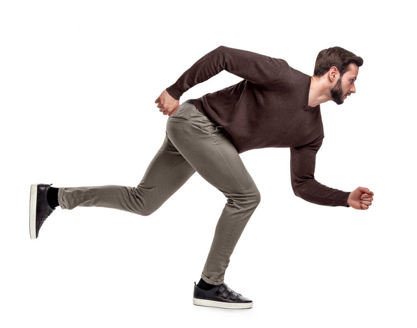 A fit bearded man in casual sweater stands in a low running position with only one foot on the ground. - Photo, image