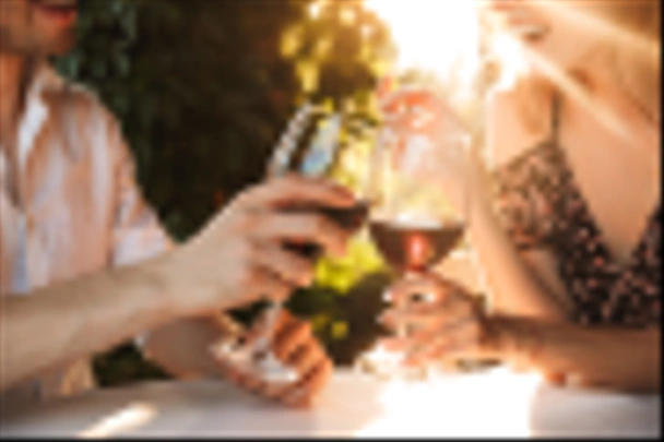 Cropped image of young loving couple sitting in cafe by dating outdors in park holding glasses of wine drinking. - Foto, imagen