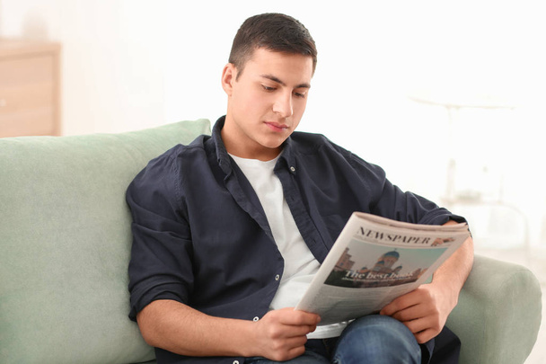 Bonito homem lendo jornal no sofá em casa
 - Foto, Imagem