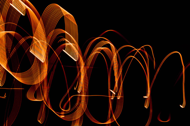 Bright orange spiral patterns from light strips on a black background - Photo, Image
