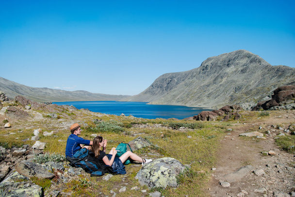 dois caminhantes descansando no cume de Besseggen sobre o lago Gjende no Parque Nacional Jotunheimen, Noruega
 - Foto, Imagem