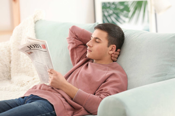 schöner Mann, der zu Hause auf dem Sofa Zeitung liest - Foto, Bild
