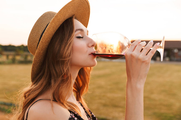 Image of cute pretty young woman outdoors holding glass drinking wine. - Fotó, kép