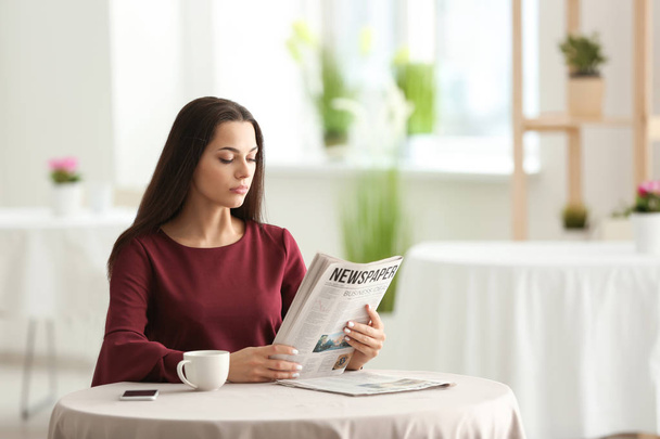 Young woman reading newspaper in cafe - Foto, Imagen