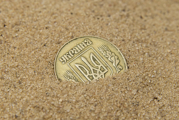 Moneda de bronce ucraniano en la arena
 - Foto, Imagen