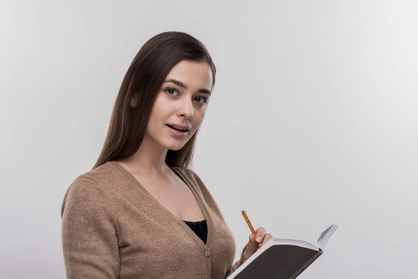 Beautiful young businesswoman holding pencil and notebook - Фото, зображення