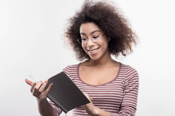 Intelligens mosolygó kellemes göndör tartó női neki fekete notebook - Fotó, kép
