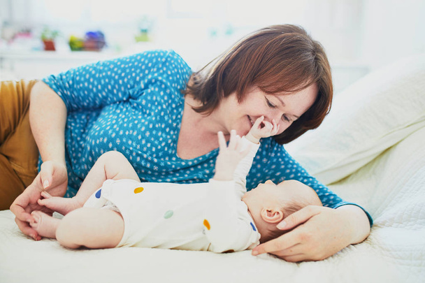 Young mother with her little daughter in nursery. Woman playing with baby girl. Family time - Foto, Bild