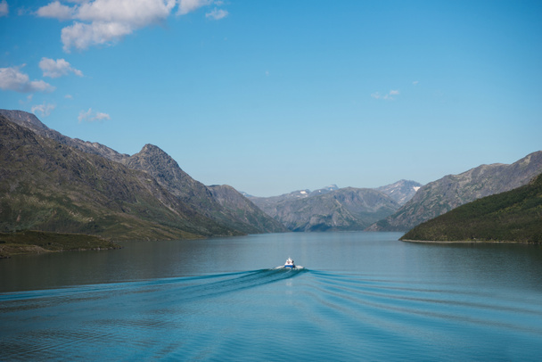 βάρκα επιπλέει στην ήρεμη γαλάζια νερά της λίμνης Gjende, κορυφογραμμή Besseggen, Jotunheimen εθνικό πάρκο, Νορβηγία  - Φωτογραφία, εικόνα
